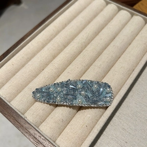 Close-up of luxury light blue rhinestone hair clip with pearls and crystals in a velvet box
