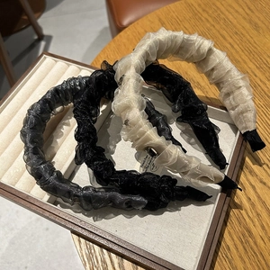 Trois serre-têtes en organza plissé noir, beige et gris sur un plateau à bijoux