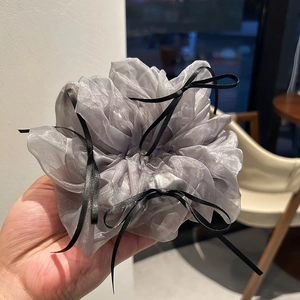 Detail of grey organza scrunchie with delicate black ribbon bows held in hand