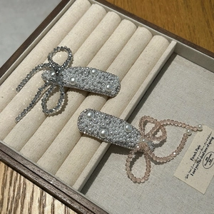 Elegant floral hair clips with pearls and crystals set in a soft beige jewelry display tray
