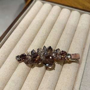 Detail of flower duckbill hair clip with brown and champagne crystals on gold base