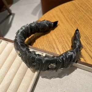 Gros plan sur un serre-tête plissé en tulle gris foncé avec des strass étincelants