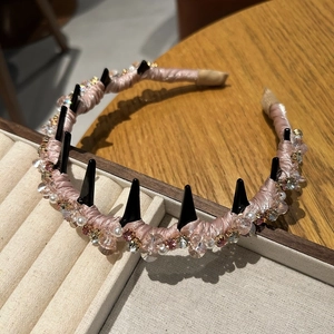 Detail of luxury pink crystal headband with black spikes and pearls on a display tray