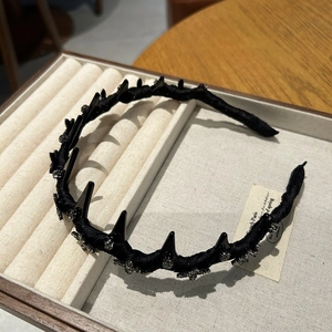 Detail of black velvet headband with punk spikes and silver rhinestone floral accents