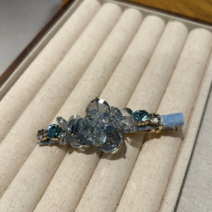 Detailed close-up of handmade crystal hair clip with blue beads on a golden alloy base