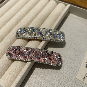 Close-up of sparkling rhinestone hair clips on a velvet tray with floral gemstone patterns