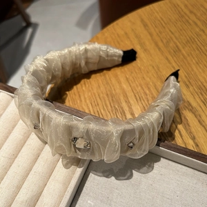 Détail du serre-tête en organza crème avec plis délicats et strass étincelants