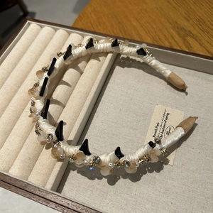 Detailed macro view of crystal embellished headband with cream satin and black spikes