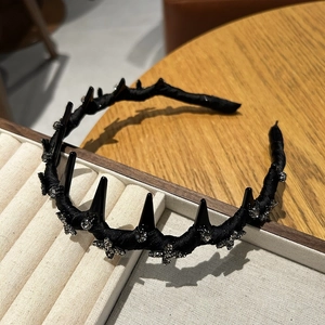 Detailed macro view of black velvet headband with spikes and rhinestone cross details