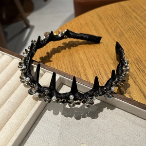 Detail of luxury punk headband with black spikes, crystals, and pearls on a velvet tray