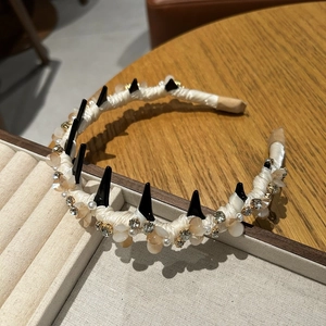 Detailed macro view of white ribbon headband with black punk spikes and crystal beads