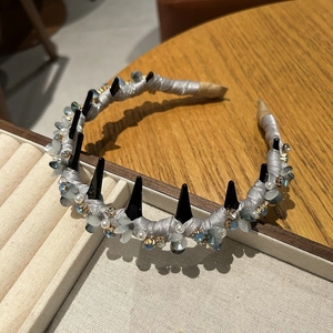 Detail view of crystal padded headband with black punk spikes and faux pearls decoration