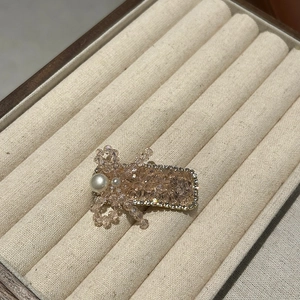 Detailaufnahme der eleganten Haarklammer mit Champagner-Kristallen und großer weißer Perle