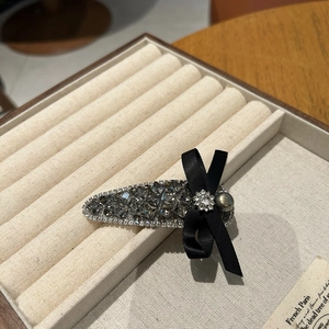 Detailed macro view of French style silver hair clip with grey crystals and black ribbon bow
