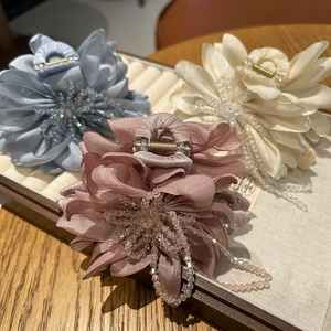 Detail of floral hair claws with satin petals, beaded stamens and tassels in three colors