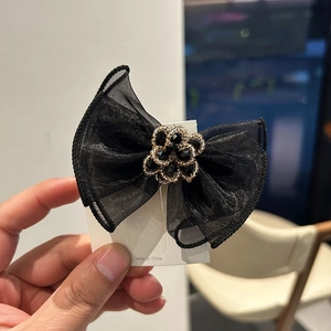 Elegant black mesh double bow hair clip with luxury rhinestone center on a display card