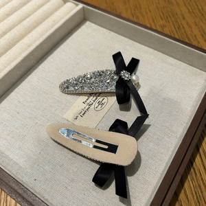 Detail of drop-shaped BB clips with rhinestones, black bow and pearl in a jewelry box
