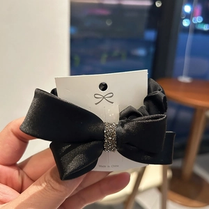 Elegant black satin bow scrunchie with sparkling silver rhinestones on a display card