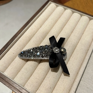 Close-up of luxury crystal bow hair clip with grey rhinestones on velvet display