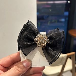 Elegant black mesh bow hair clip with central crystal flower bead on a white card display