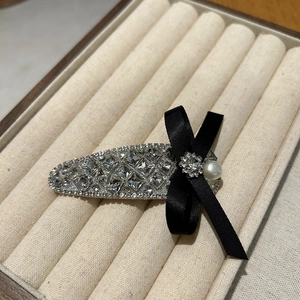 Detail of luxury teardrop hair clip with inlaid crystals and a black silk ribbon bow