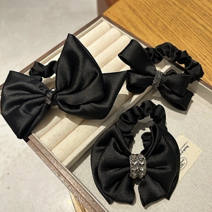 Close-up of black satin bow hair ties with shimmering rhinestone centers set of three