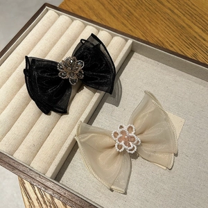 Detail of layered tulle bow clips with rhinestones and pearls on a velvet tray