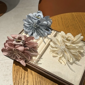 Detail of elegant silk flower hair claws with crystal bead tassels in pastel colors