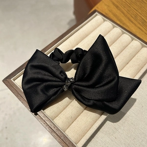 Close-up of black satin bow hair tie with sparkling crystal centerpiece on a display tray