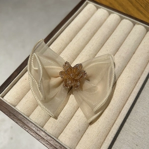 Detailed macro view of cream organza bow hair clip with amber beaded flower centerpiece