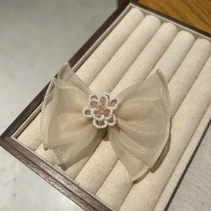 Detail of elegant beige mesh bow hair clip with handmade pearl flower and soft texture