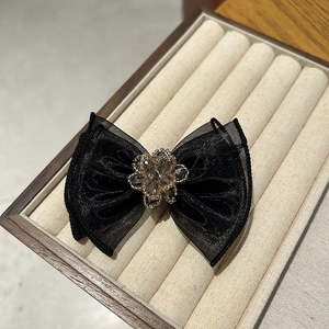 Detailed close-up of a black tulle bow clip with an intricate grey beaded flower centerpiece