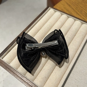 Detail of black mesh bow hair clip with sparkling rhinestone pendant and metal duckbill clip