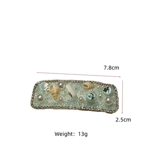 Detail view of a vintage shell and pearl hair clip with dimensions 7.8cm and 13g weight