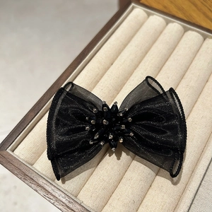Détail du nœud en organza noir avec centre en cristal dans un écrin à bijoux en velours