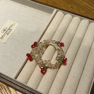 Detail of handmade beaded ring with red crystal cherries on a champagne gold band