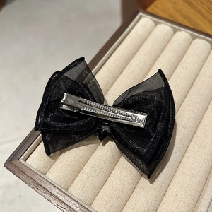 Détail d'une élégante pince à cheveux noeud en organza noir avec strass sur plateau