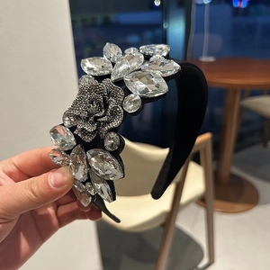 Close-up of luxury black velvet headband with sparkling crystals and a 3D rose detail