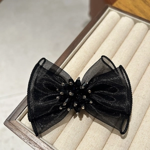 Détail d'une élégante pince à cheveux noeud en organza noir avec perles et cristaux
