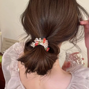 Detailed view of colorful crystal beaded hair tie styling a low bun on dark hair