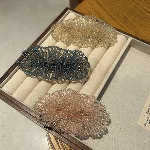 Close-up of handmade beaded hair clips with luxury crystals in champagne, blue, and pink colors