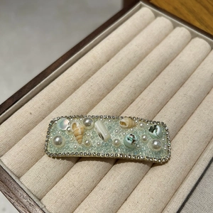Detailed shot of shell and pearl hair clip with light blue resin and sparkling rhinestones
