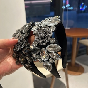 Detailed view of hand-held wide headbands with luxury crystals and floral embellishments
