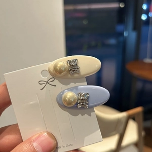 Close-up of bear-shaped rhinestone hair clips in cream and light blue resin