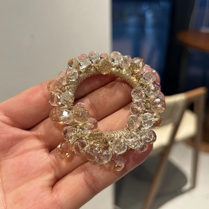 Detail of beaded hair tie with sparkling faceted crystals and golden elastic band