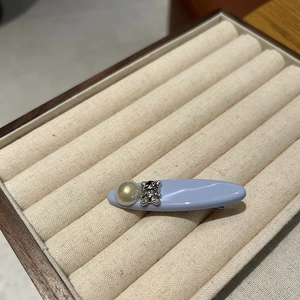 Detail of light blue hair clip with rhinestone bear and pearl in a jewelry box