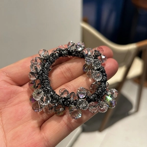 Detailed view of elastic hair tie with faceted crystal beads reflecting colorful light