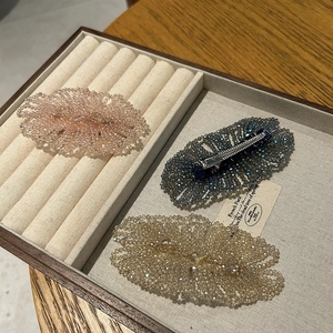 Macro detail of handmade crystal beaded hair clips with metal duckbill clasp on velvet tray