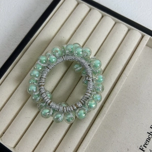 Macro detail of jelly green translucent beads with silver wire wrapping on a hair tie