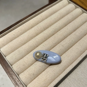 Detailed view of a blue oval hair clip with golden pearl and a rhinestone bear icon